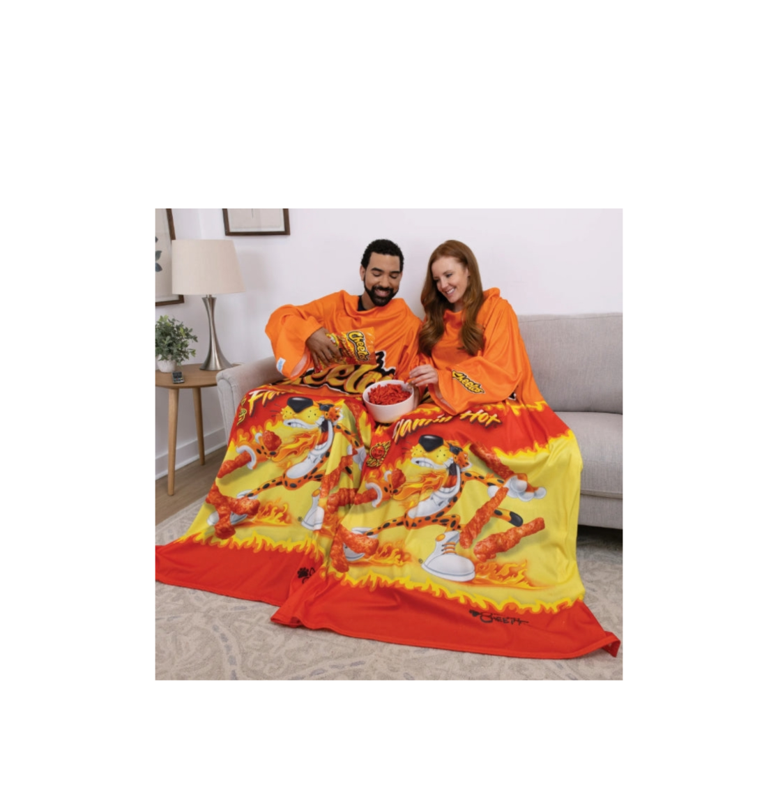 Snuggie Wearable Blanket Cheetos Flamin Hot Boxed Couple Wearing In A Relaxed Home Setting